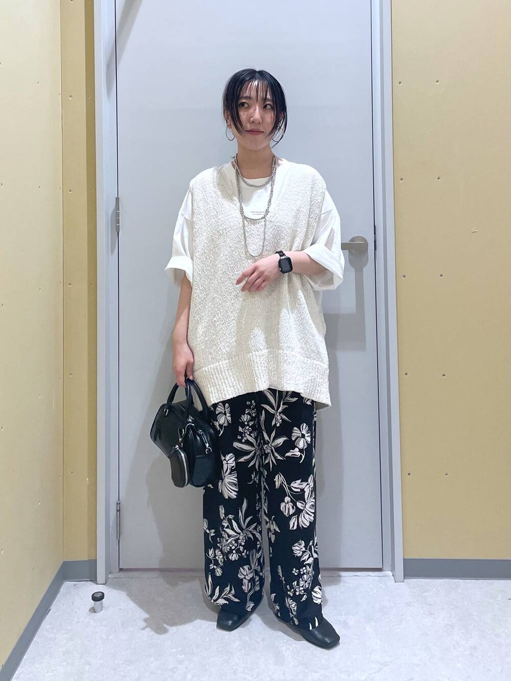 ホワイト系のニット/セーター、ホワイト系のTシャツ/カットソー、ブラック系のショルダーバッグを着用したレディースの春コーディネートの3枚目の写真