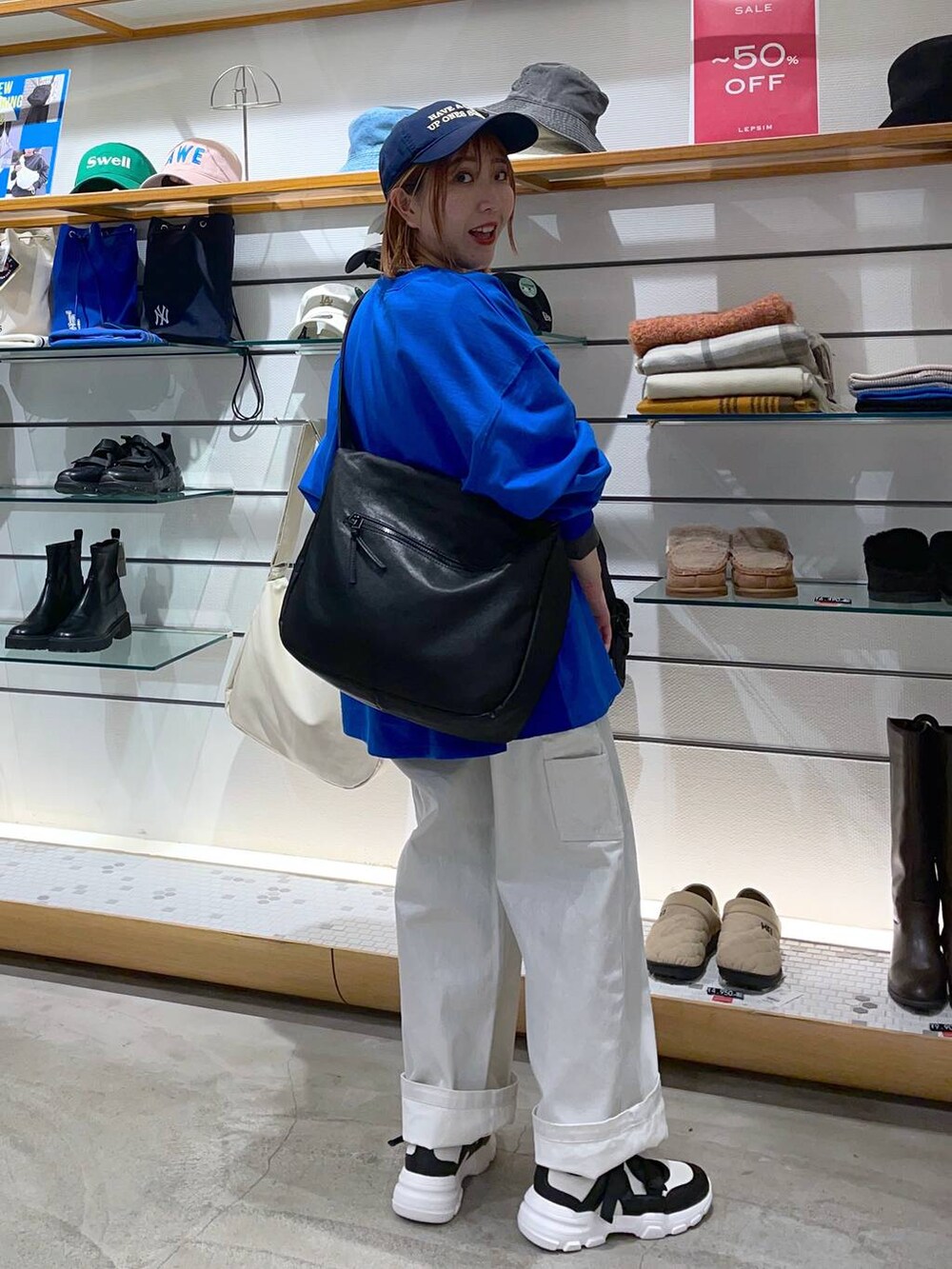 ブラック系のショルダーバッグ、ブルー系のTシャツ/カットソー、ホワイト系のスニーカーを着用したレディースの春コーディネートの2枚目の写真