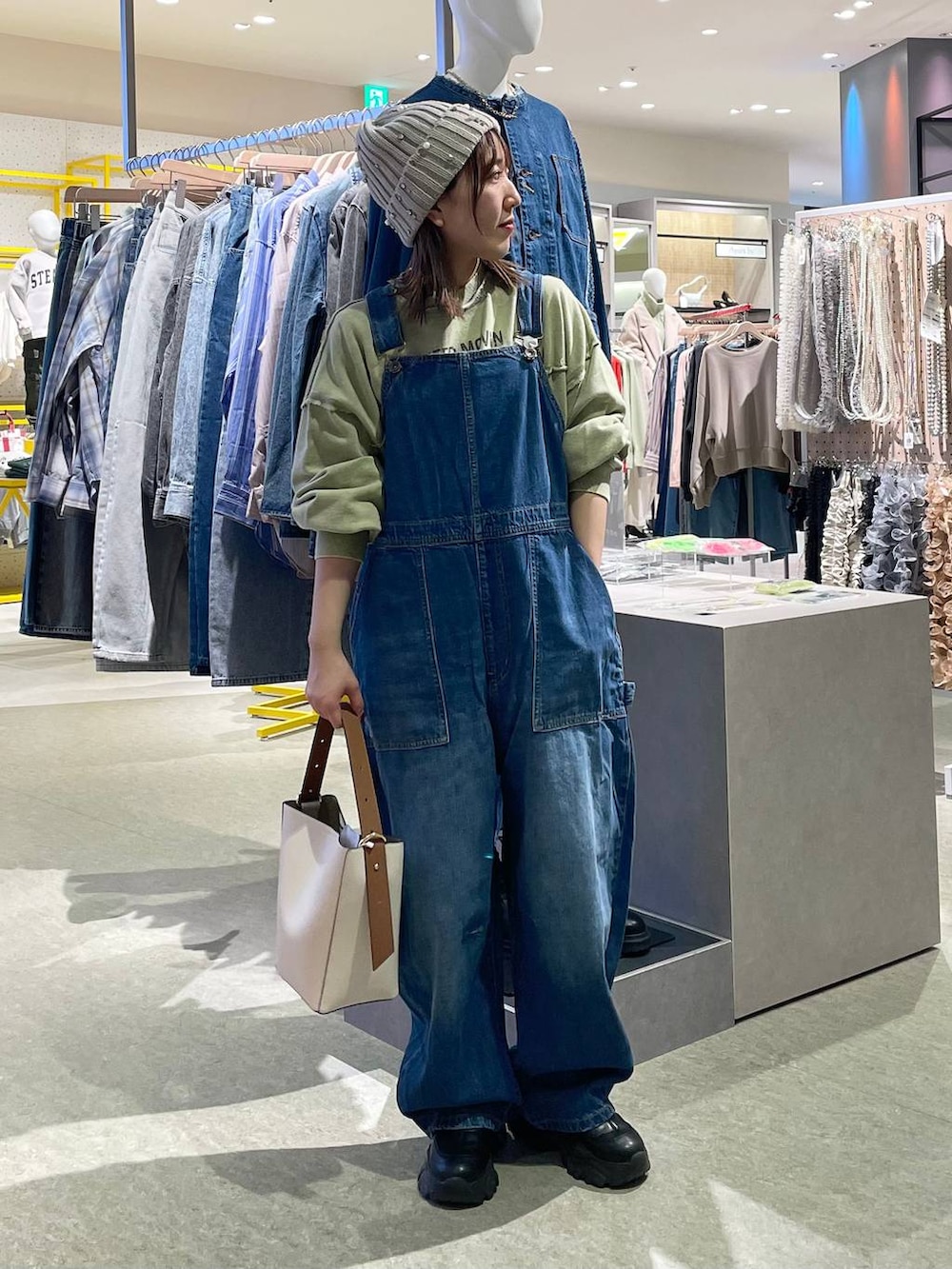 ブルー系のサロペット/オーバーオール、ホワイト系のショルダーバッグ、グリーン系のスウェットを着用したレディースの冬コーディネートの3枚目の写真