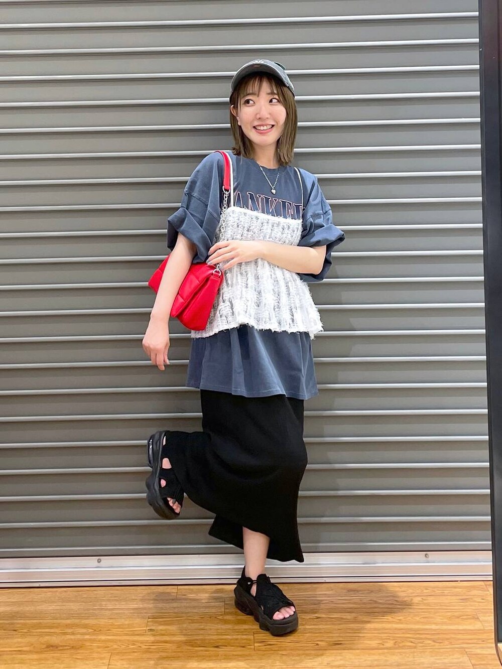 レッド系のショルダーバッグ、ブルー系のTシャツ/カットソー、ブラック系のスカートを着用したレディースの夏コーディネートの2枚目の写真