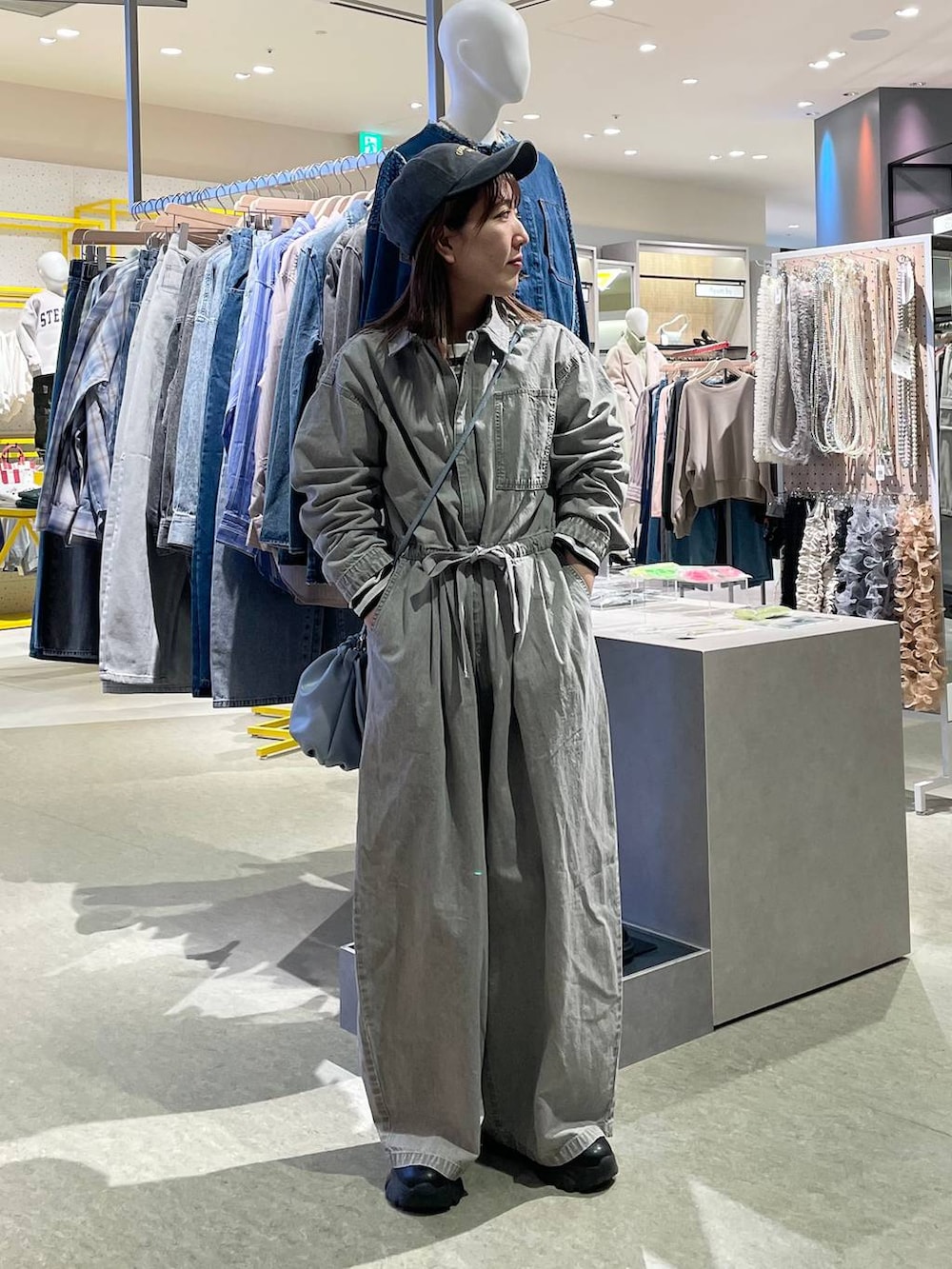 グレー系のつなぎ/オールインワン、ブルー系のショルダーバッグ、ブラック系のキャップを着用したレディースの冬コーディネートの3枚目の写真