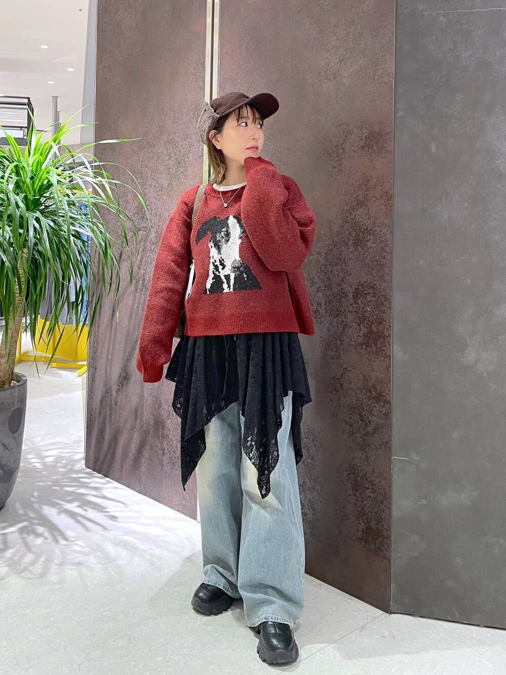 ブルー系のデニムパンツ、ブラウン系のショルダーバッグ、レッド系のニット/セーターを着用したレディースの秋コーディネートの2枚目の写真