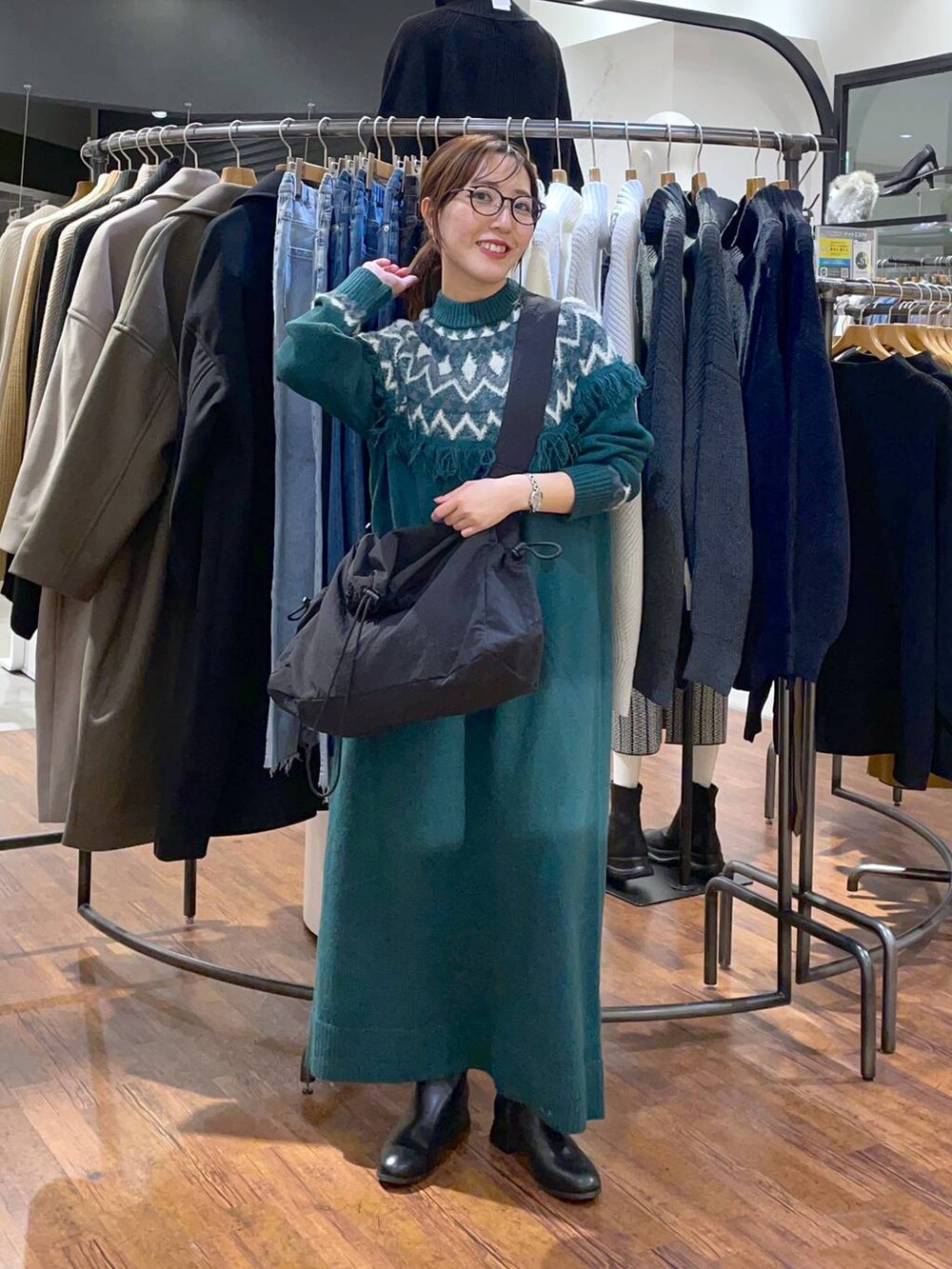 ブラック系のブーツ、グリーン系のワンピース、ブラック系のショルダーバッグを着用したレディースの冬コーディネートの2枚目の写真