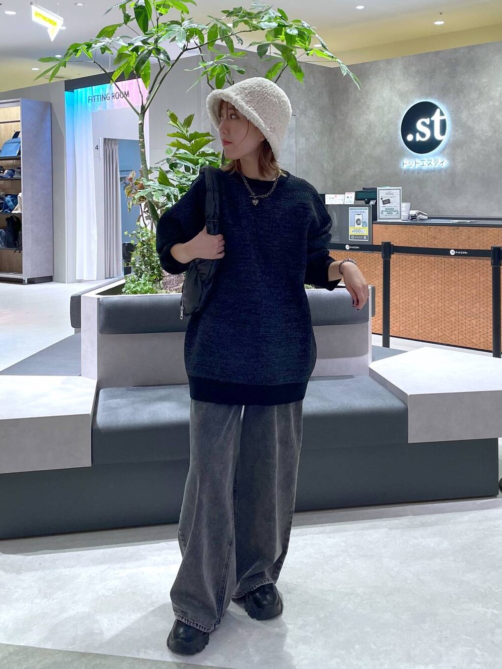 ブラック系のハンドバッグ、ブラック系のニット/セーター、グレー系のデニムパンツを着用したレディースの秋コーディネートの2枚目の写真