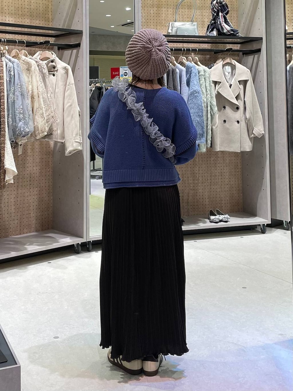 ベージュ系のワンピース、ブルー系のニット/セーター、グレー系のスマホグッズを着用したレディースの冬コーディネートの3枚目の写真