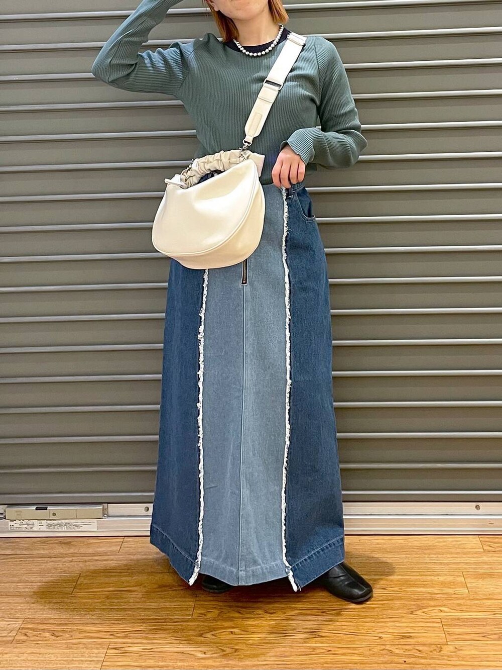ホワイト系のショルダーバッグ、ブルー系のデニムスカート、グリーン系のTシャツ/カットソーを着用したレディースの春コーディネートの2枚目の写真