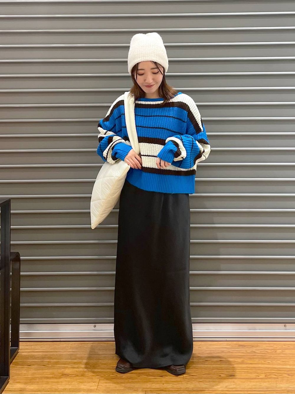 ブラック系のスカート、ホワイト系のトートバッグ、ブルー系のニット/セーターを着用したレディースの冬コーディネートの2枚目の写真