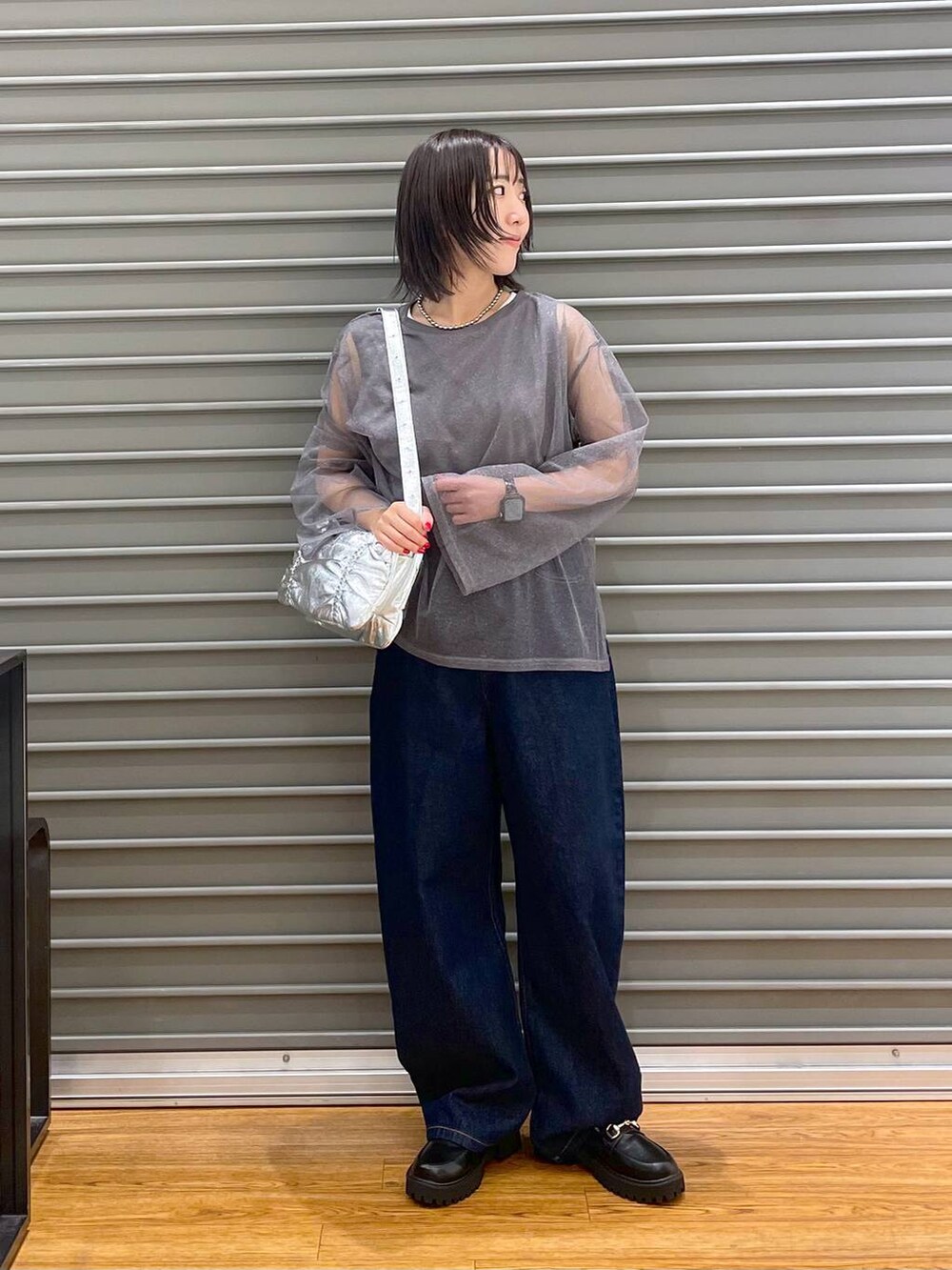 シルバー系のショルダーバッグ、ブラック系のローファー、ブルー系のデニムパンツを着用したレディースの秋コーディネートの2枚目の写真