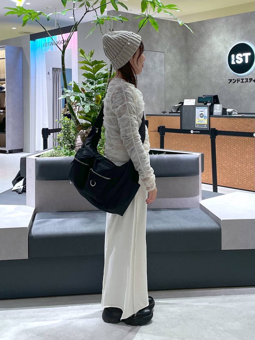 ブラック系のショルダーバッグ、ブラック系のブーツ、ホワイト系のスウェットパンツを着用したレディースの冬コーディネートの2枚目の写真