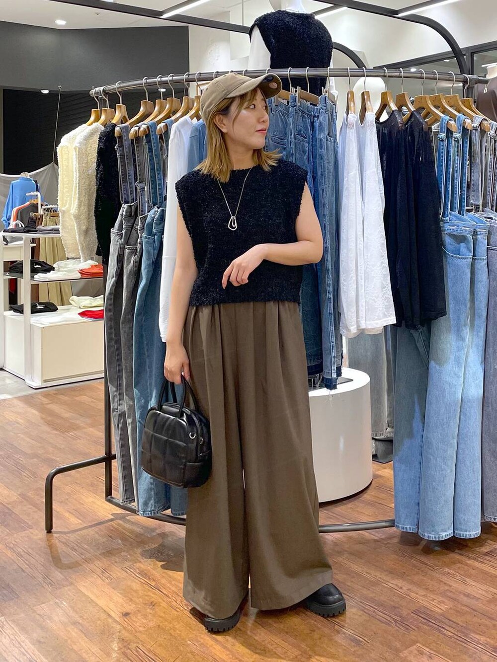 ブラウン系のスラックス、ブラック系のローファー、ブラック系のボストンバッグを着用したレディースの秋コーディネートの2枚目の写真