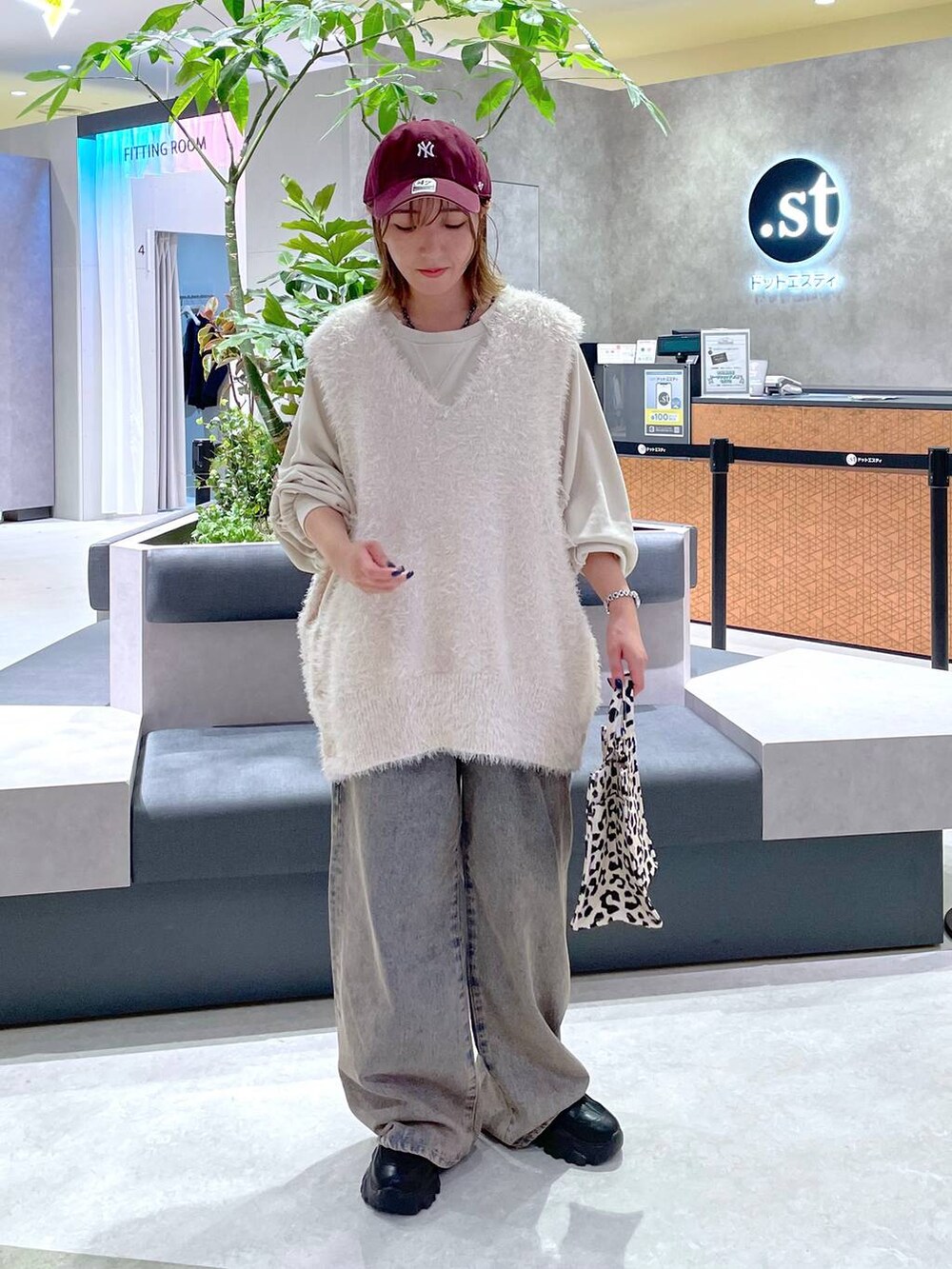 ベージュ系のTシャツ/カットソー、ホワイト系のベスト、ブルー系のデニムパンツを着用したレディースの秋コーディネートの2枚目の写真