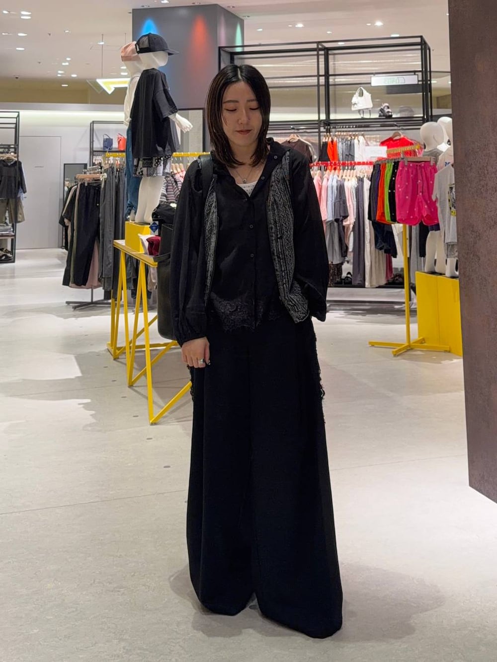 ブラック系のトートバッグ、ブラック系のスラックス、ブラック系のベストを着用したレディースの夏コーディネートの2枚目の写真