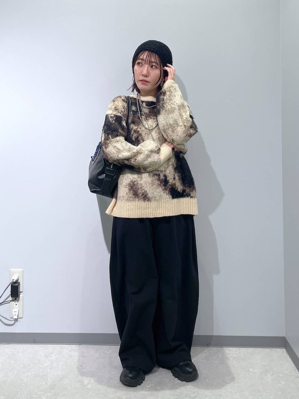 ブラウン系のニット/セーター、ブラック系のボストンバッグ、ブラック系のスウェットパンツを着用したレディースの冬コーディネートの2枚目の写真