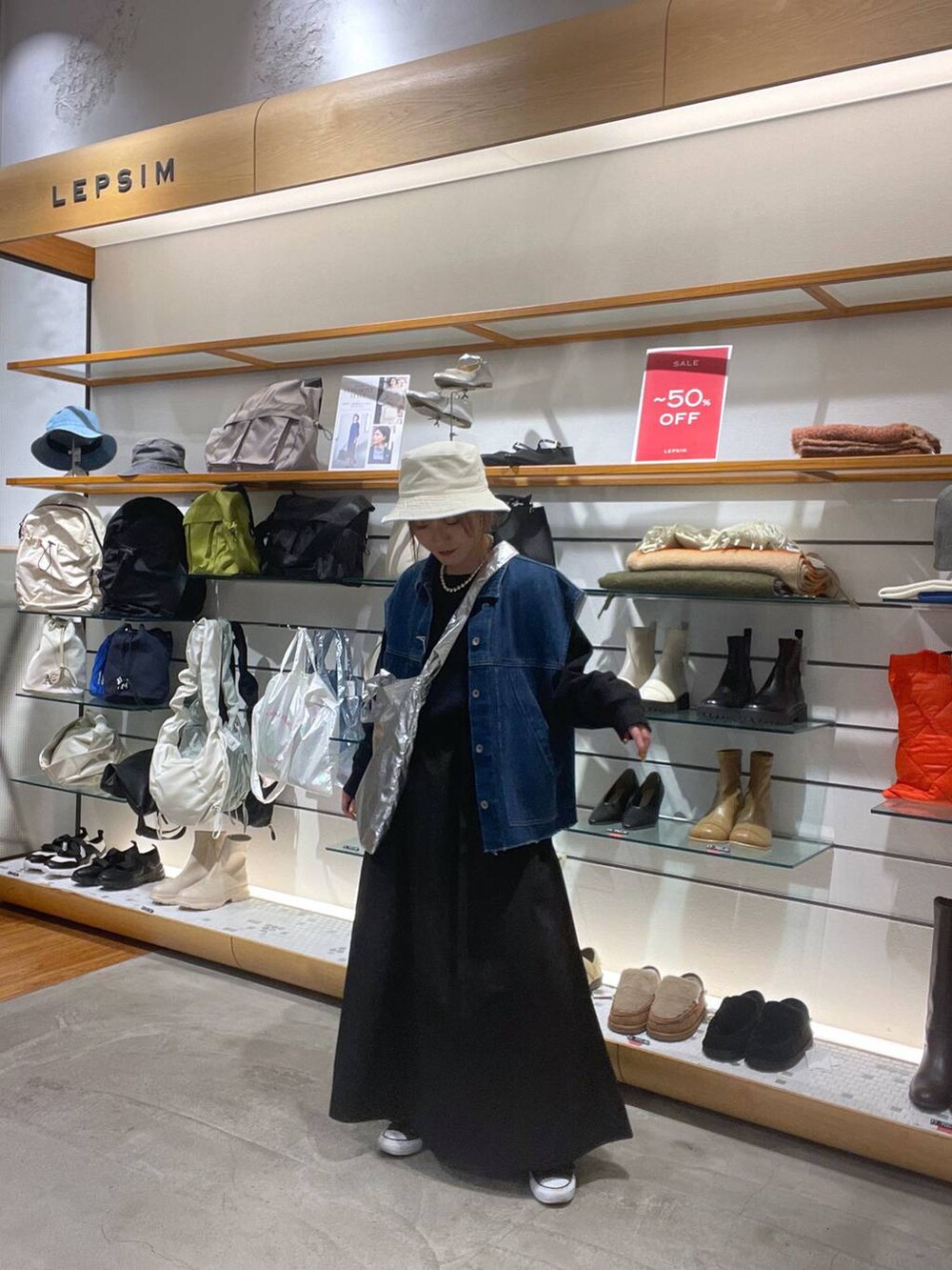 ブラック系のワンピース、シルバー系のトートバッグ、ブルー系のベストを着用したレディースの春コーディネートの3枚目の写真