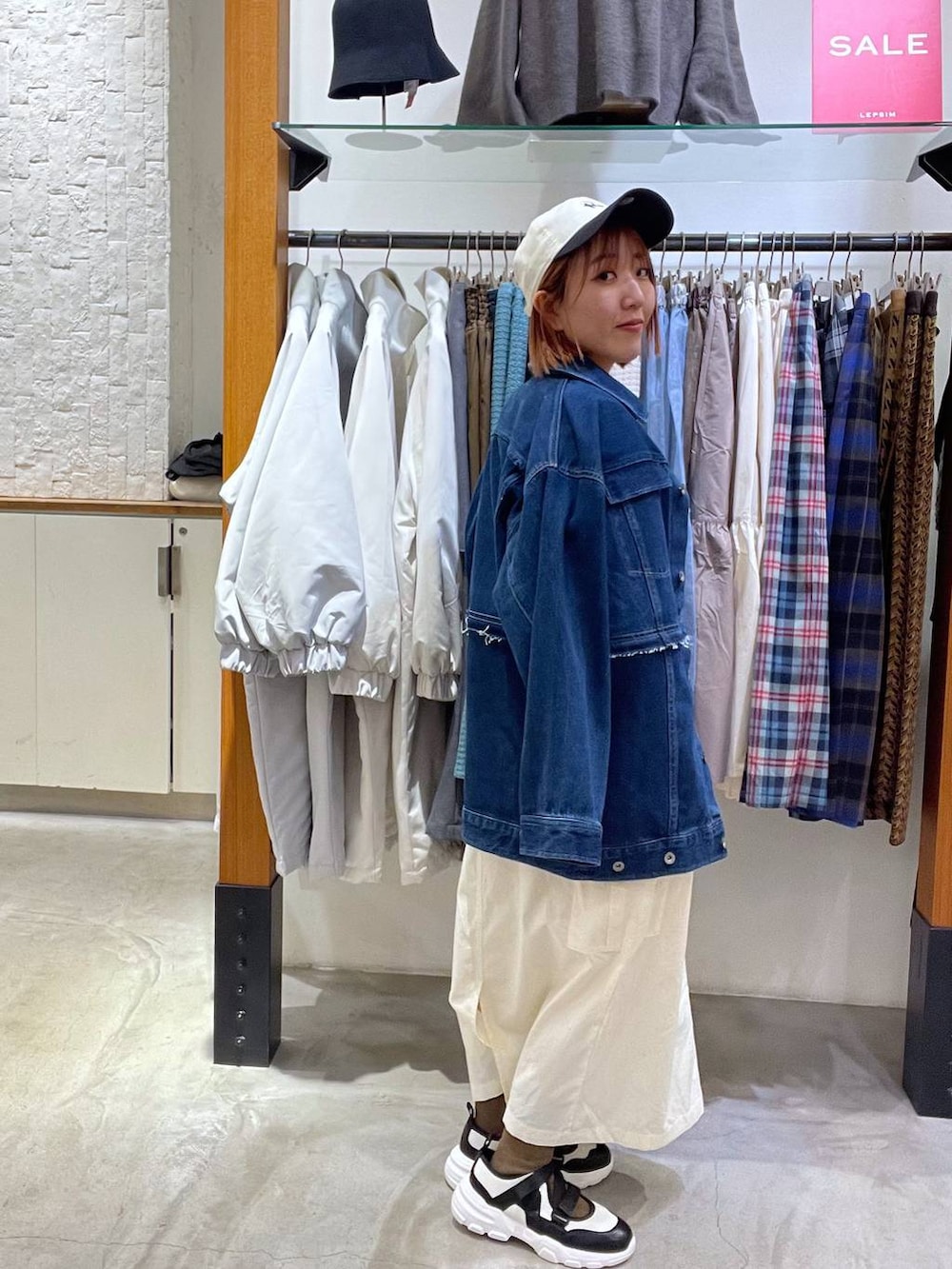 オレンジ系のスウェット、ブルー系のデニムジャケット、ホワイト系のスニーカーを着用したレディースの冬コーディネートの2枚目の写真