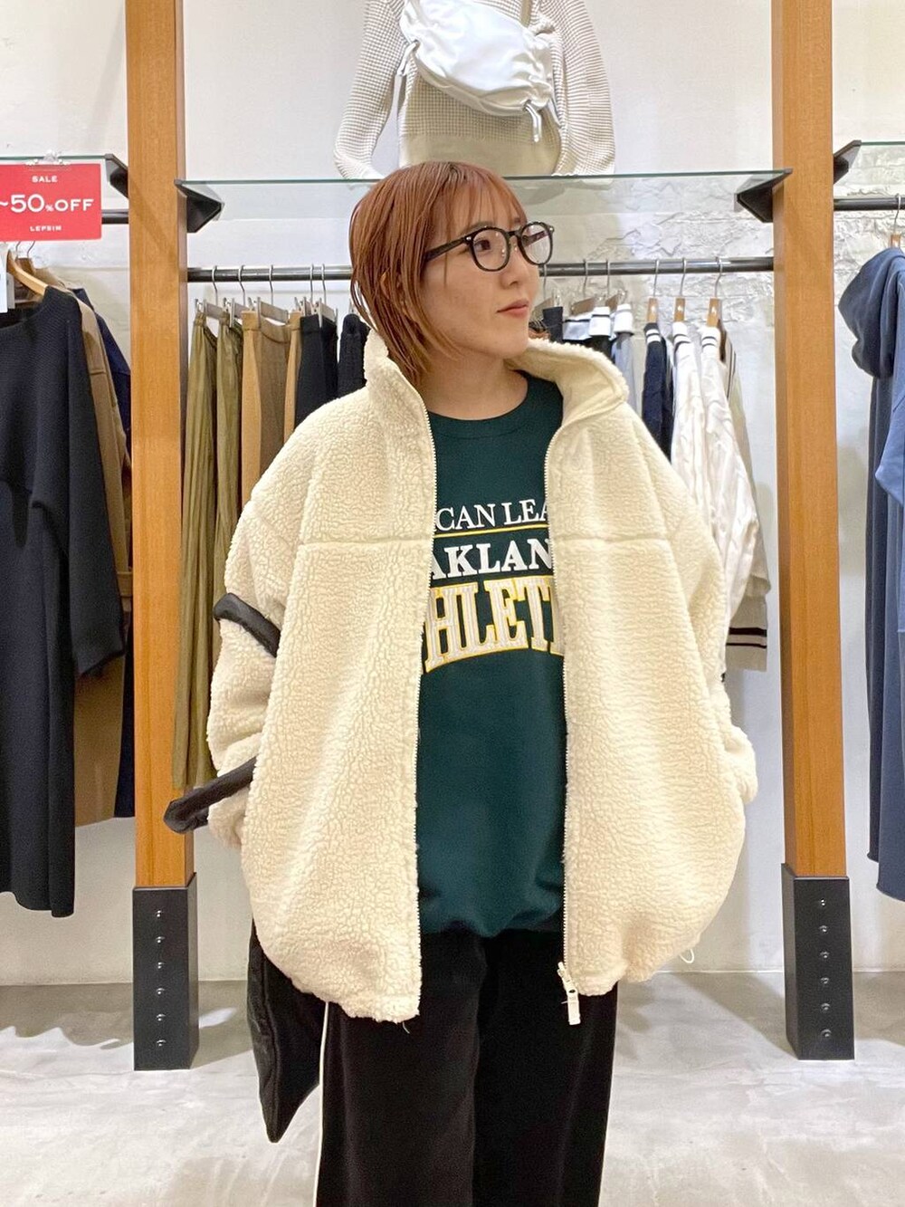 グリーン系のスウェット、ブラック系のトートバッグ、ホワイト系のその他アウターを着用したレディースの冬コーディネートの3枚目の写真