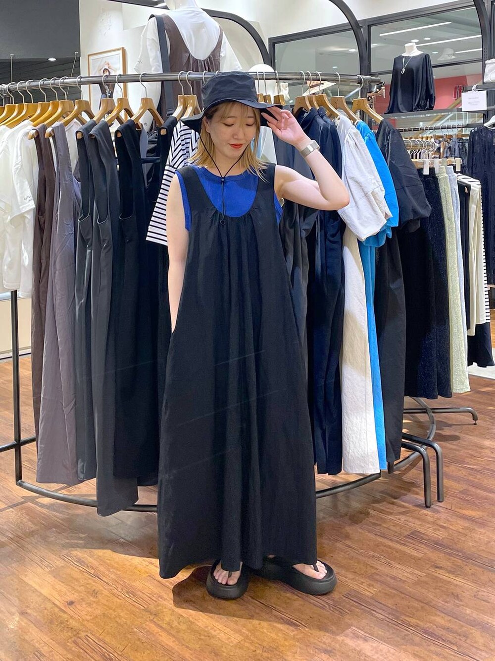 ブラック系のサンダル、ブルー系のタンクトップ、ブラック系のジャンパースカートを着用したレディースの夏コーディネートの2枚目の写真