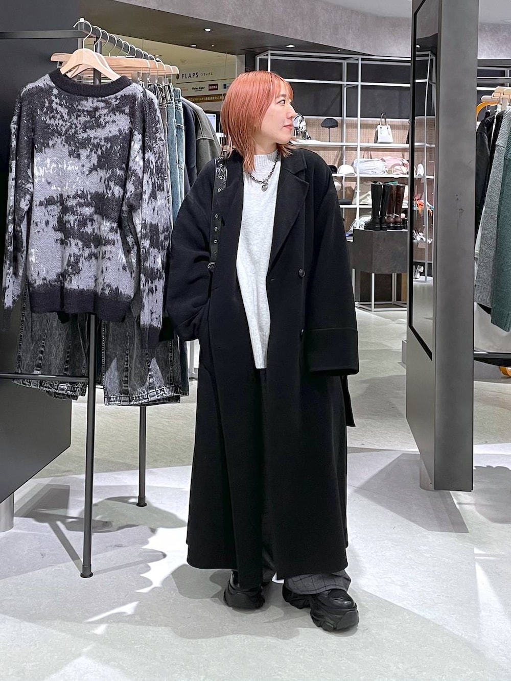 ブラック系のチェスターコート、グレー系のニット/セーター、ブラック系のショルダーバッグを着用したレディースの秋コーディネートの2枚目の写真