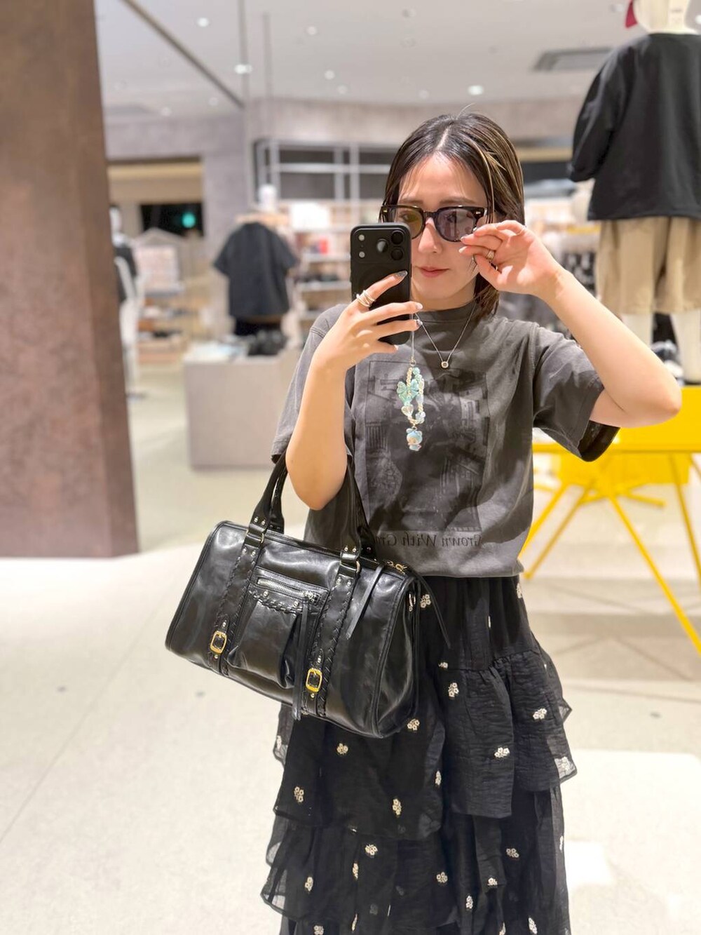 ブラック系のボストンバッグ、ブラック系のスカート、ブラック系のTシャツ/カットソーを着用したレディースの夏コーディネートの4枚目の写真