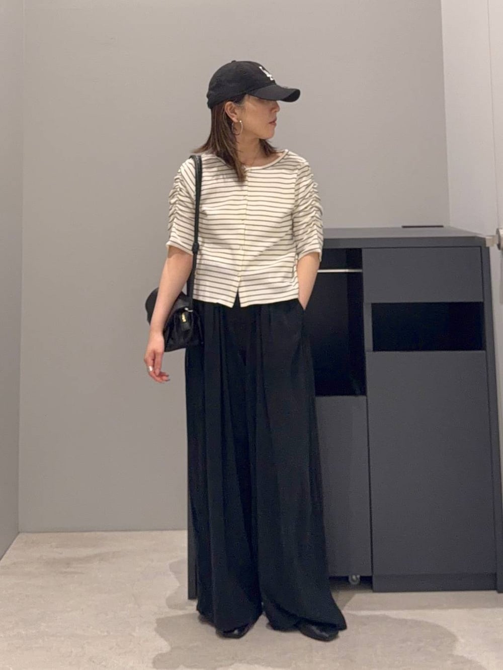 ブラック系のその他パンツ、ブラック系のショルダーバッグ、ホワイト系のTシャツ/カットソーを着用したレディースの夏コーディネートの2枚目の写真