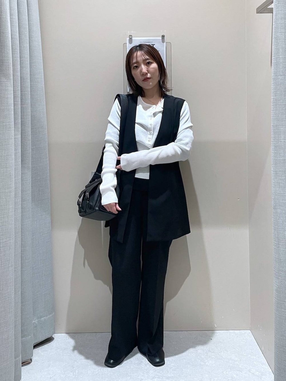 ブラック系のその他アウター、ホワイト系のニット/セーター、ブラック系のショルダーバッグを着用したレディースの冬コーディネートの2枚目の写真