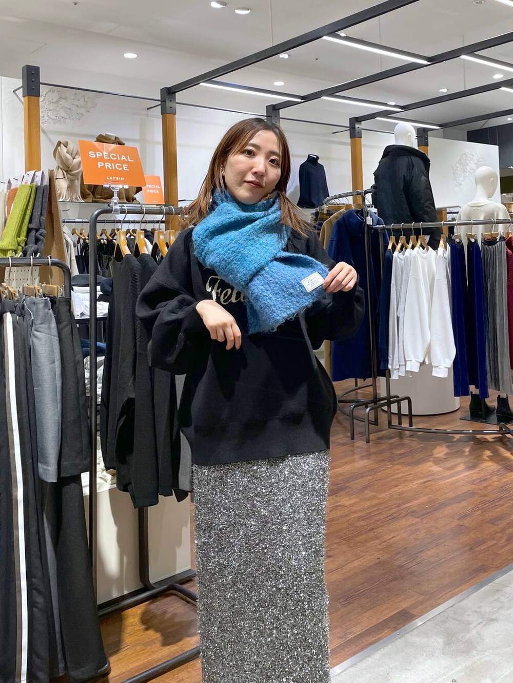 ブラック系のニット/セーター、ブラック系のスカート、ブルー系のストール/ショールを着用したレディースの冬コーディネートの2枚目の写真