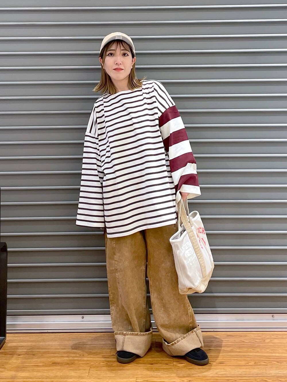 ブラウン系のデニムパンツ、レッド系のTシャツ/カットソー、ブラック系のスニーカーを着用したレディースの秋コーディネートの2枚目の写真