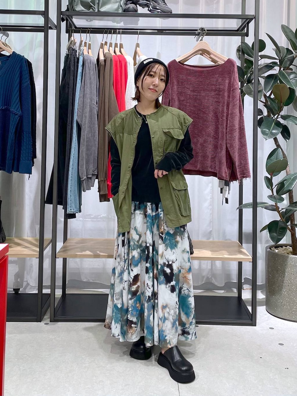 グリーン系のベスト、ブラック系のTシャツ/カットソー、ブルー系のスカートを着用したレディースの秋コーディネートの2枚目の写真