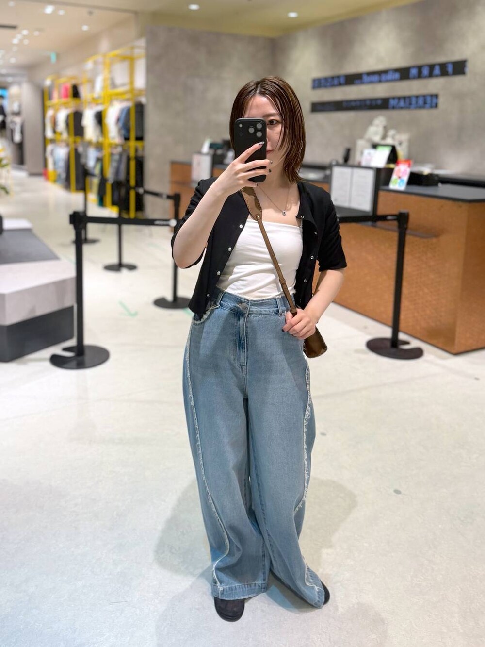 ブルー系のデニムパンツ、ブラック系のTシャツ/カットソー、ブラウン系のショルダーバッグを着用したレディースの夏コーディネートの3枚目の写真