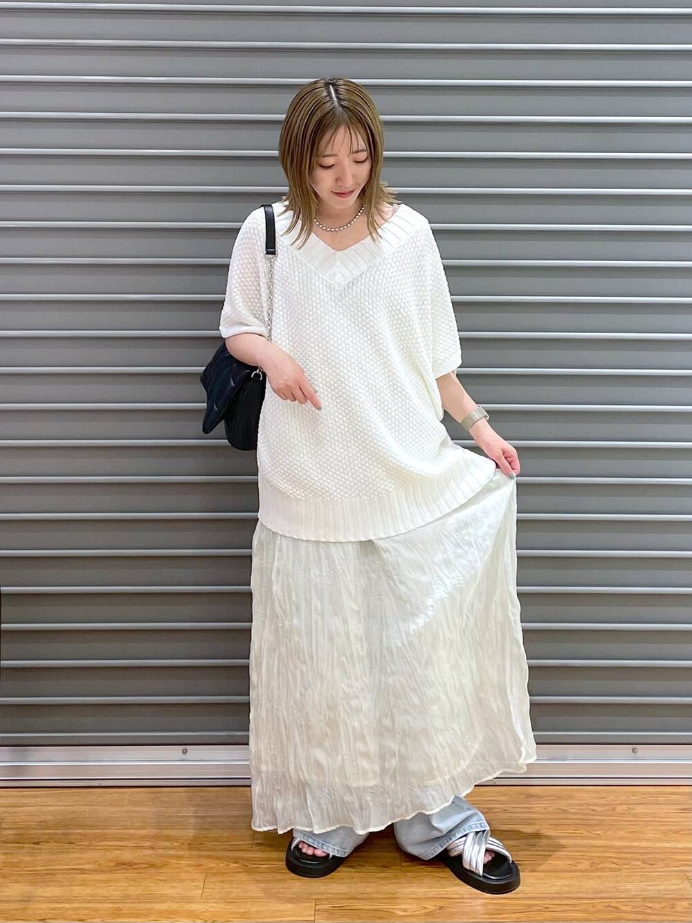 ブラック系のショルダーバッグ、ブルー系のデニムパンツ、シルバー系のサンダルを着用したレディースの夏コーディネートの2枚目の写真