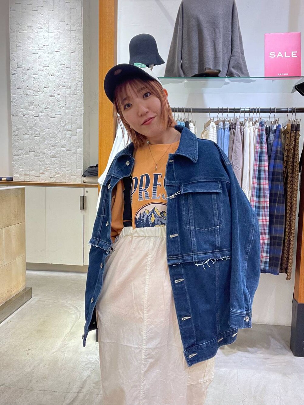 オレンジ系のスウェット、ブルー系のデニムジャケット、ホワイト系のスニーカーを着用したレディースの冬コーディネートの4枚目の写真