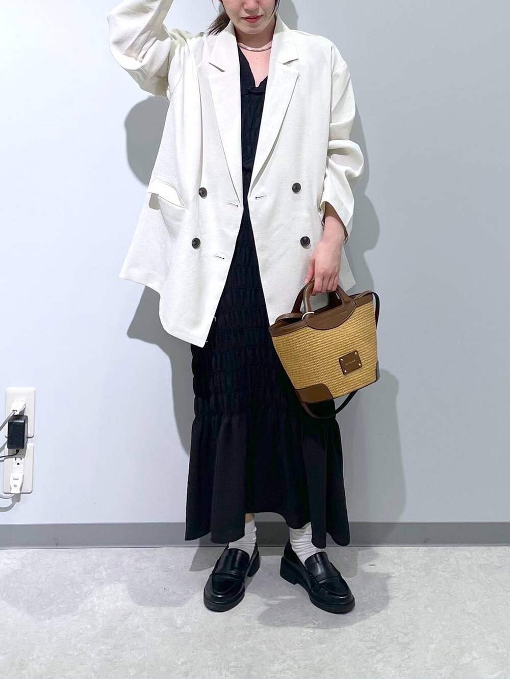 ホワイト系のテーラードジャケット、ブラウン系のショルダーバッグ、ブラック系のワンピースを着用したレディースの春コーディネートの2枚目の写真