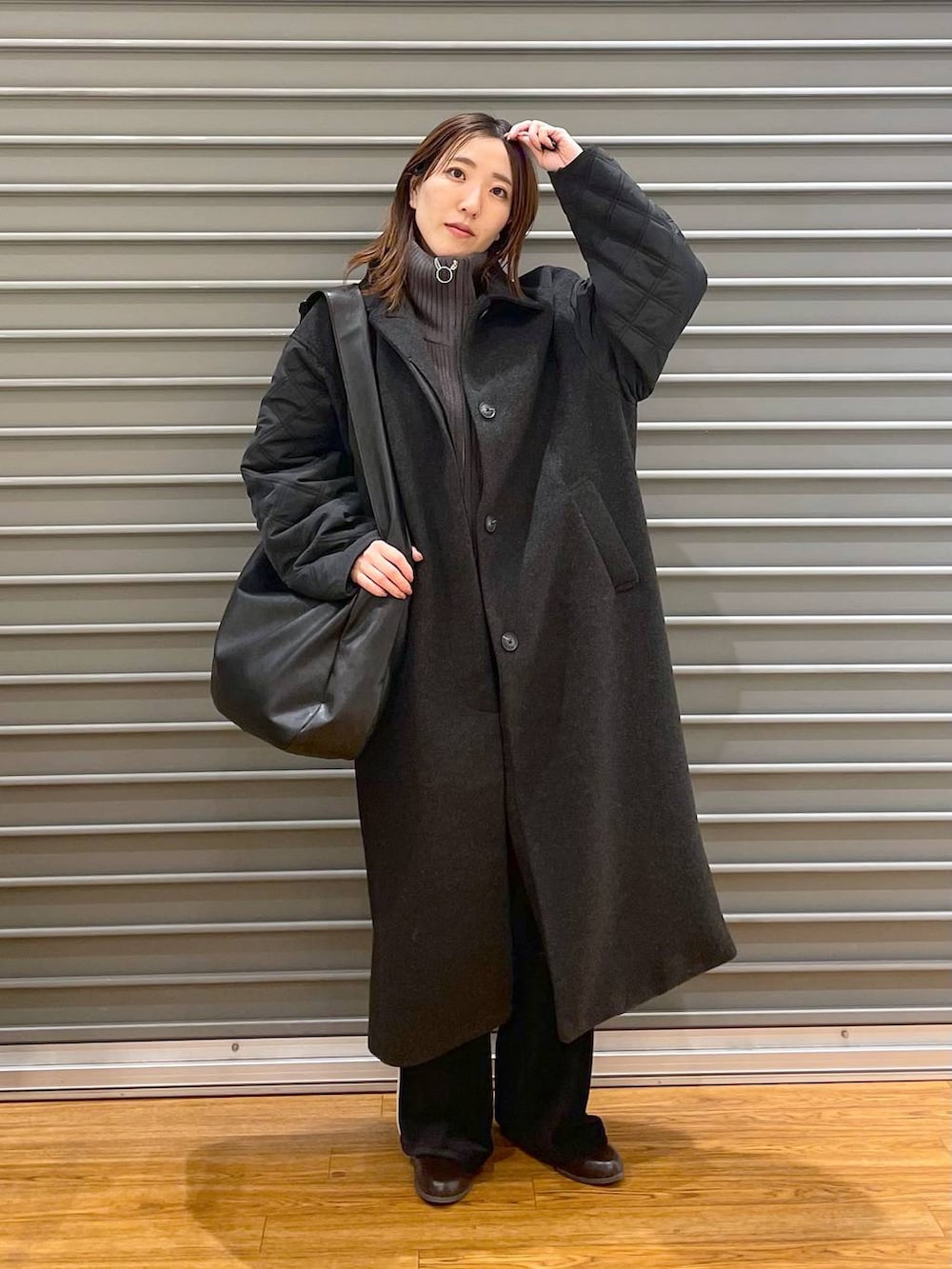 ブラック系のショルダーバッグ、ブラウン系のブーツ、グレー系のニット/セーターを着用したレディースの冬コーディネートの2枚目の写真