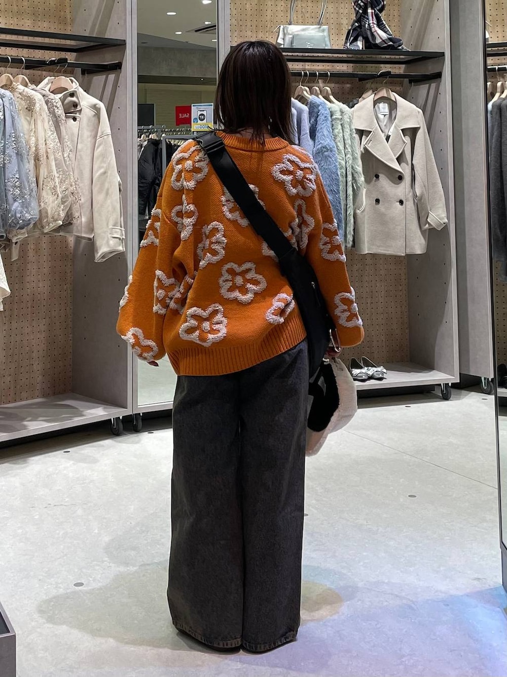 ブラック系のショルダーバッグ、ブラック系のデニムパンツ、オレンジ系のニット/セーターを着用したレディースの冬コーディネートの3枚目の写真