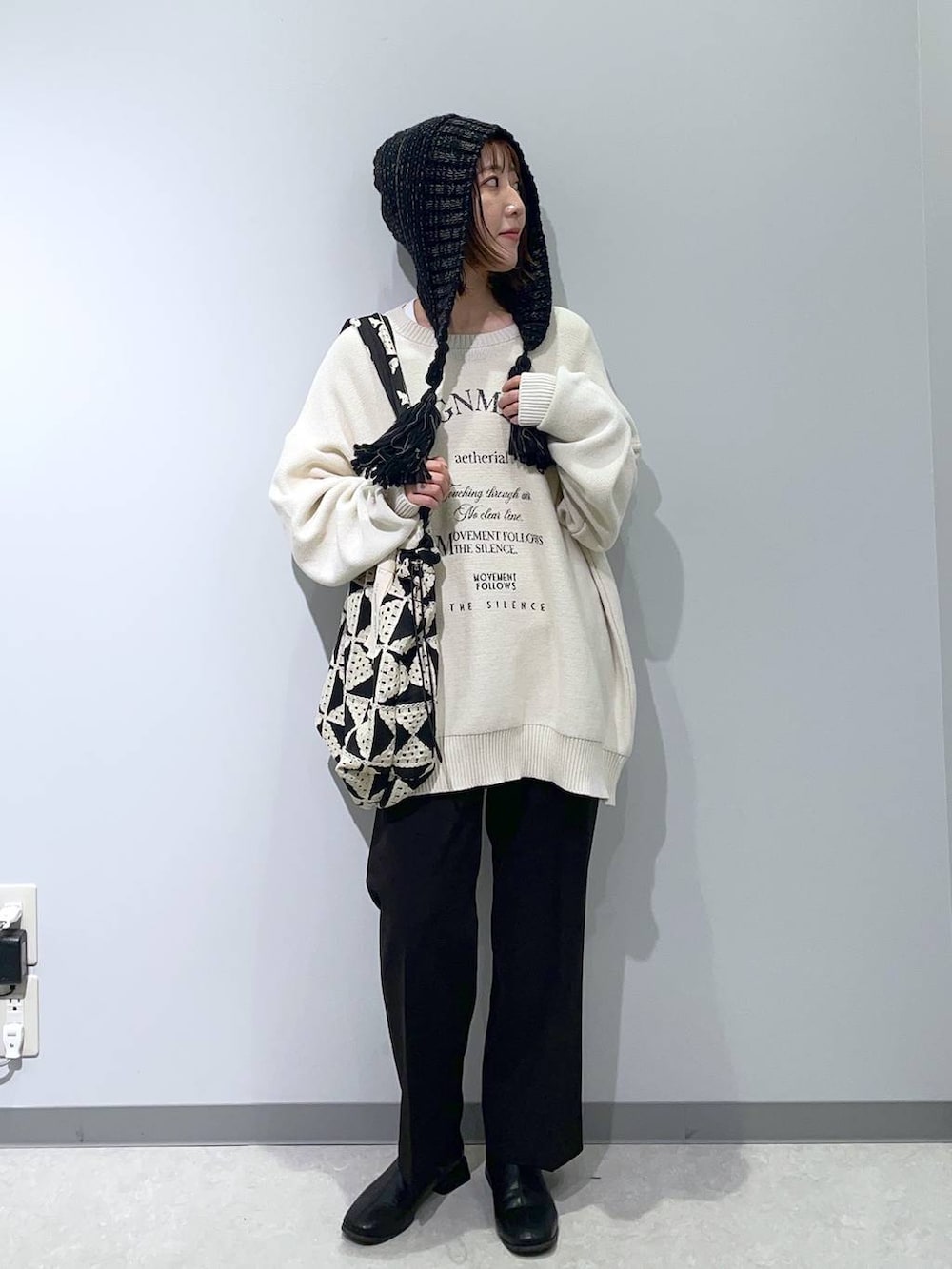 ブラック系のスラックス、その他のトートバッグ、ホワイト系のニット/セーターを着用したレディースの秋コーディネートの2枚目の写真