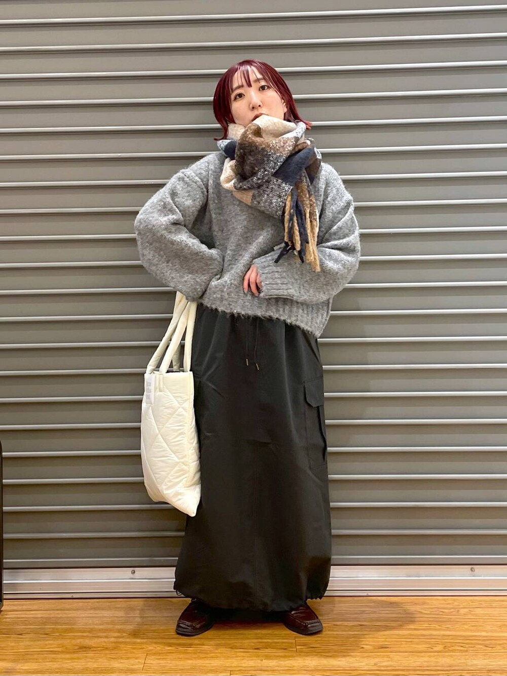 ホワイト系のトートバッグ、グレー系のスカート、グレー系のニット/セーターを着用したレディースの冬コーディネートの2枚目の写真