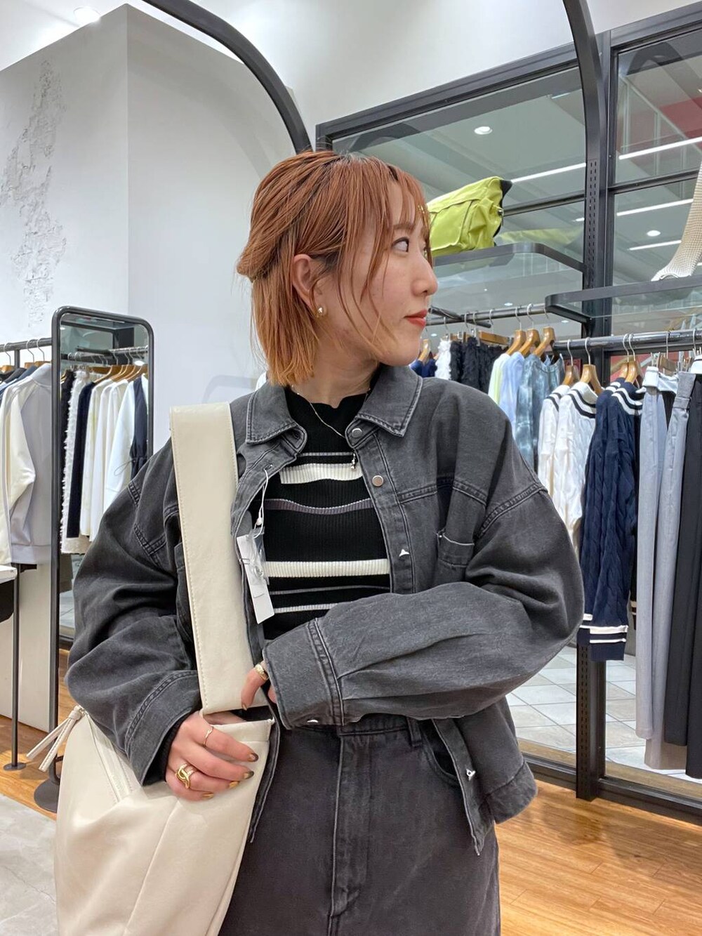 ホワイト系のショルダーバッグ、グレー系のシャツ/ブラウス、ブラック系のニット/セーターを着用したレディースの春コーディネートの3枚目の写真