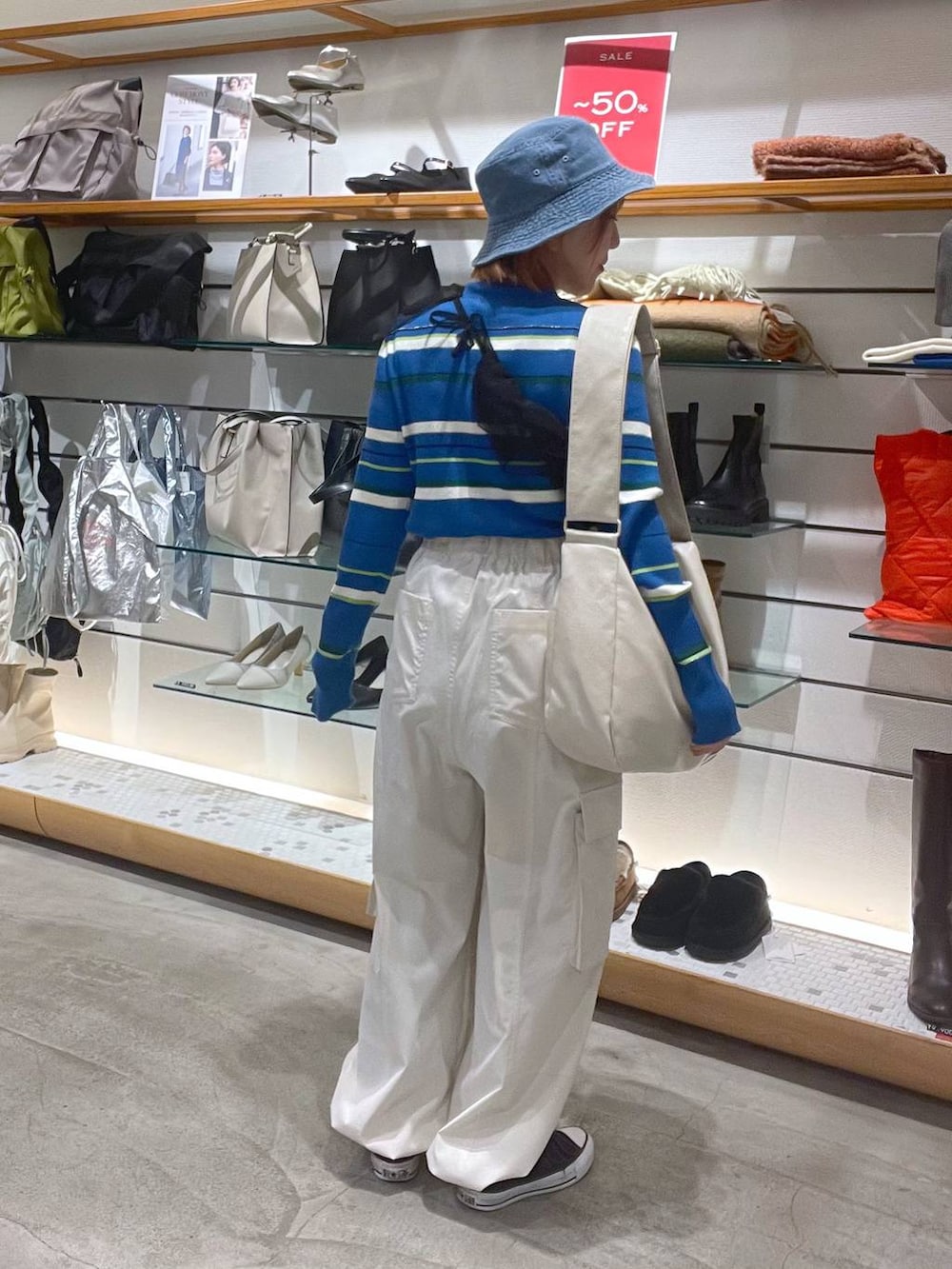 ホワイト系のショルダーバッグ、ホワイト系のカーゴパンツ、ブルー系のニット/セーターを着用したレディースの春コーディネートの2枚目の写真