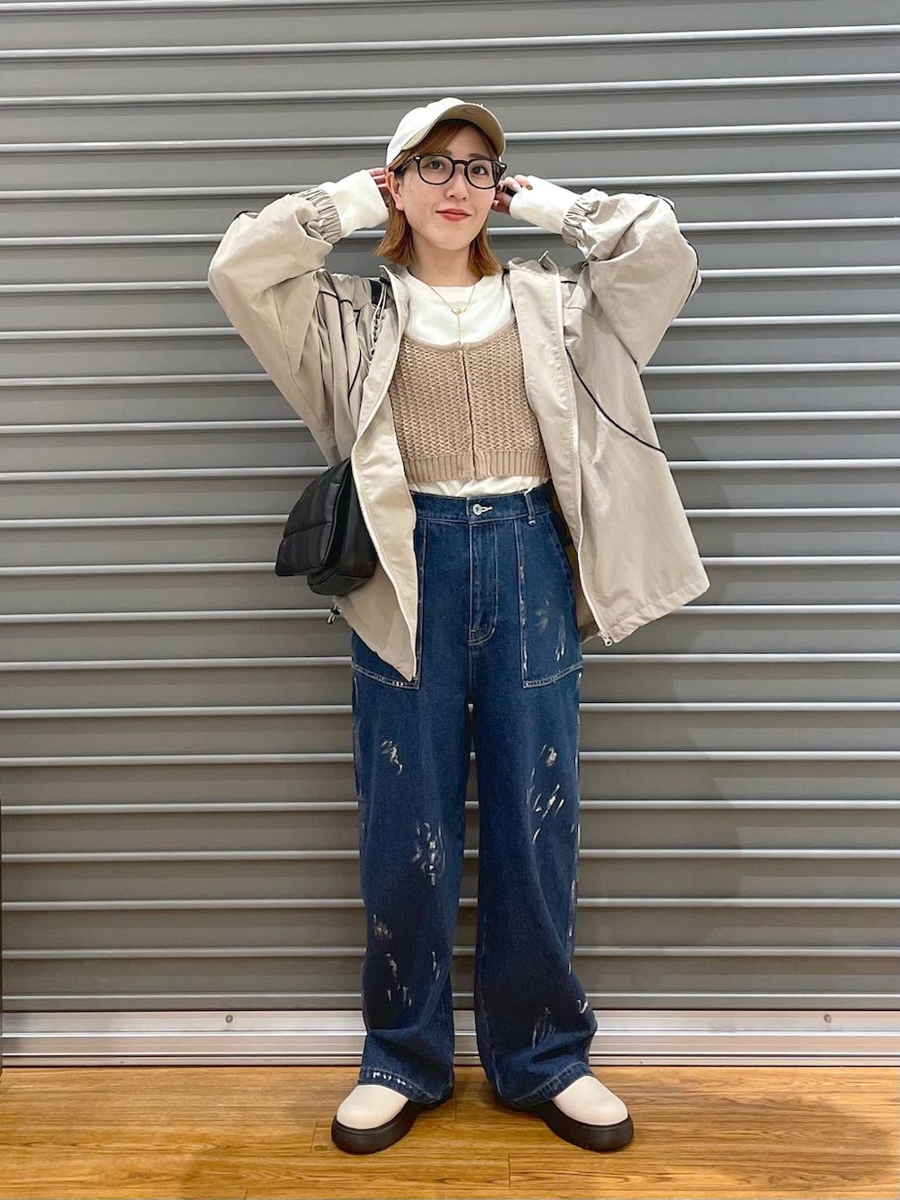 ブラック系のショルダーバッグ、ベージュ系のニット/セーター、ブルー系のデニムパンツを着用したレディースの春コーディネートの2枚目の写真