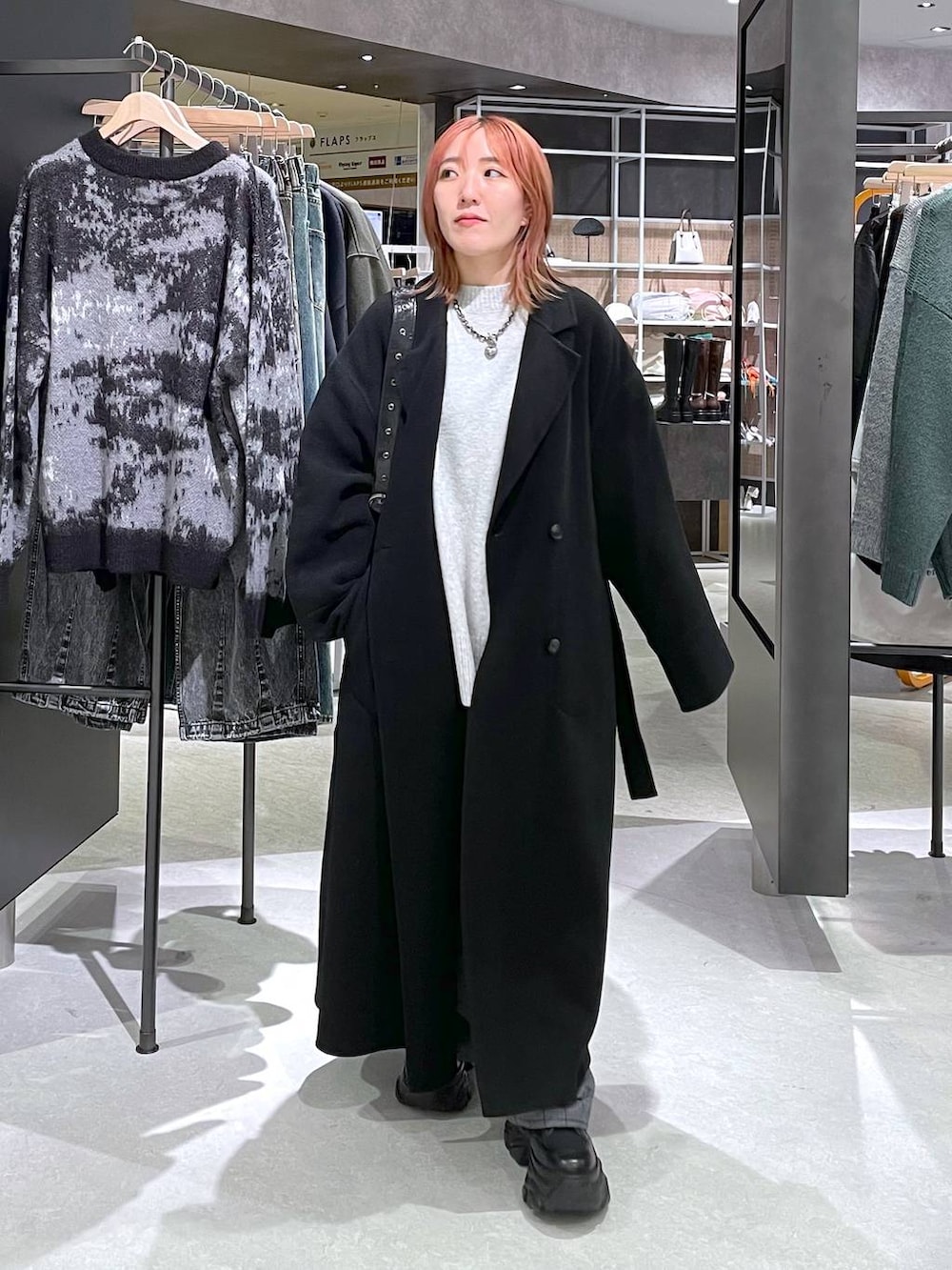 ブラック系のチェスターコート、グレー系のニット/セーター、ブラック系のショルダーバッグを着用したレディースの秋コーディネートの4枚目の写真