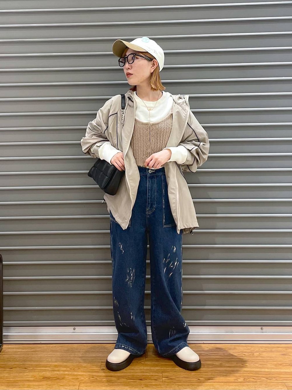 ブラック系のショルダーバッグ、ベージュ系のニット/セーター、ブルー系のデニムパンツを着用したレディースの春コーディネートの4枚目の写真