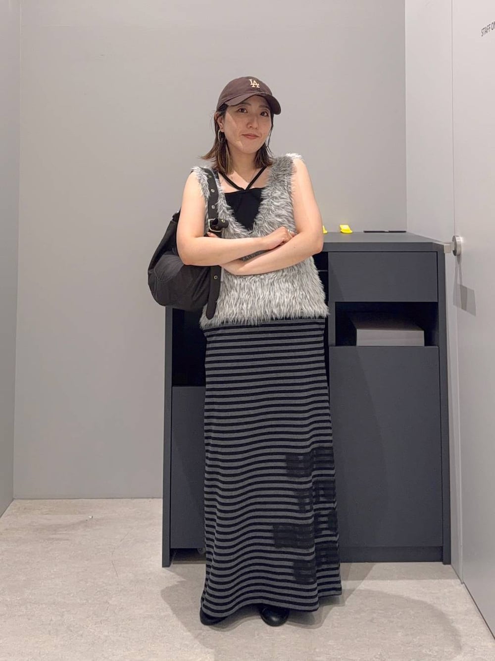 ブラック系のバレエシューズ、グレー系のベスト、ブラック系のショルダーバッグを着用したレディースの夏コーディネートの2枚目の写真