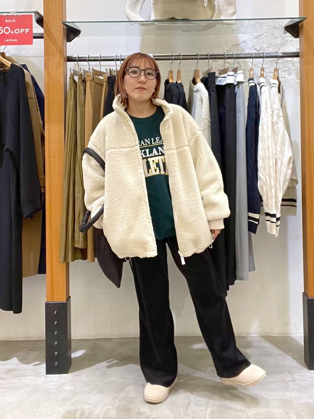 グリーン系のスウェット、ブラック系のトートバッグ、ホワイト系のその他アウターを着用したレディースの冬コーディネートの2枚目の写真