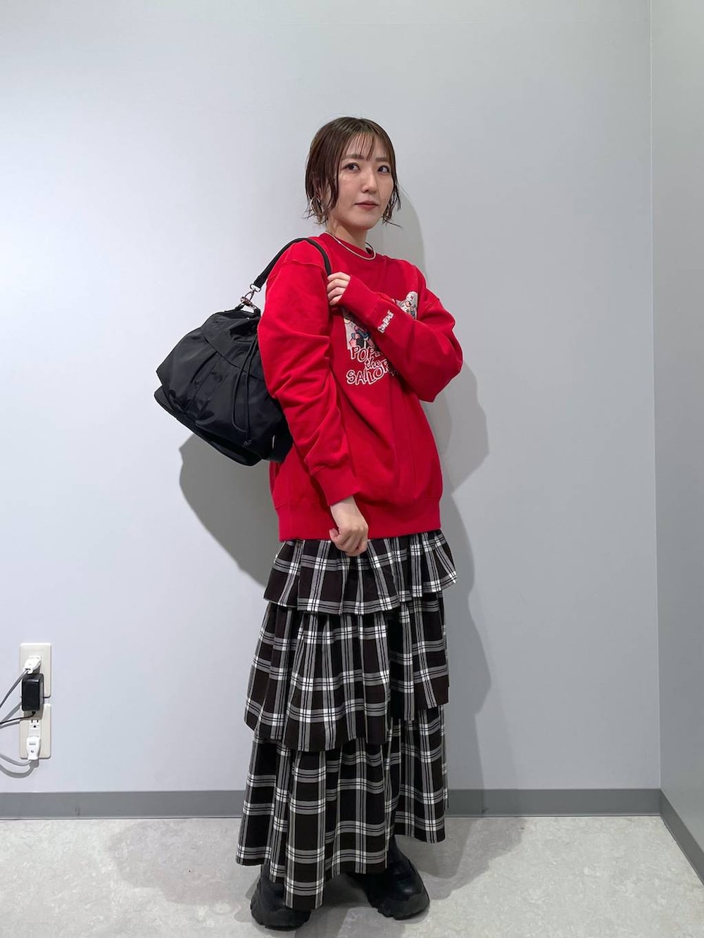 ブラック系のショルダーバッグ、ホワイト系のスカート、レッド系のスウェットを着用したレディースの冬コーディネートの2枚目の写真