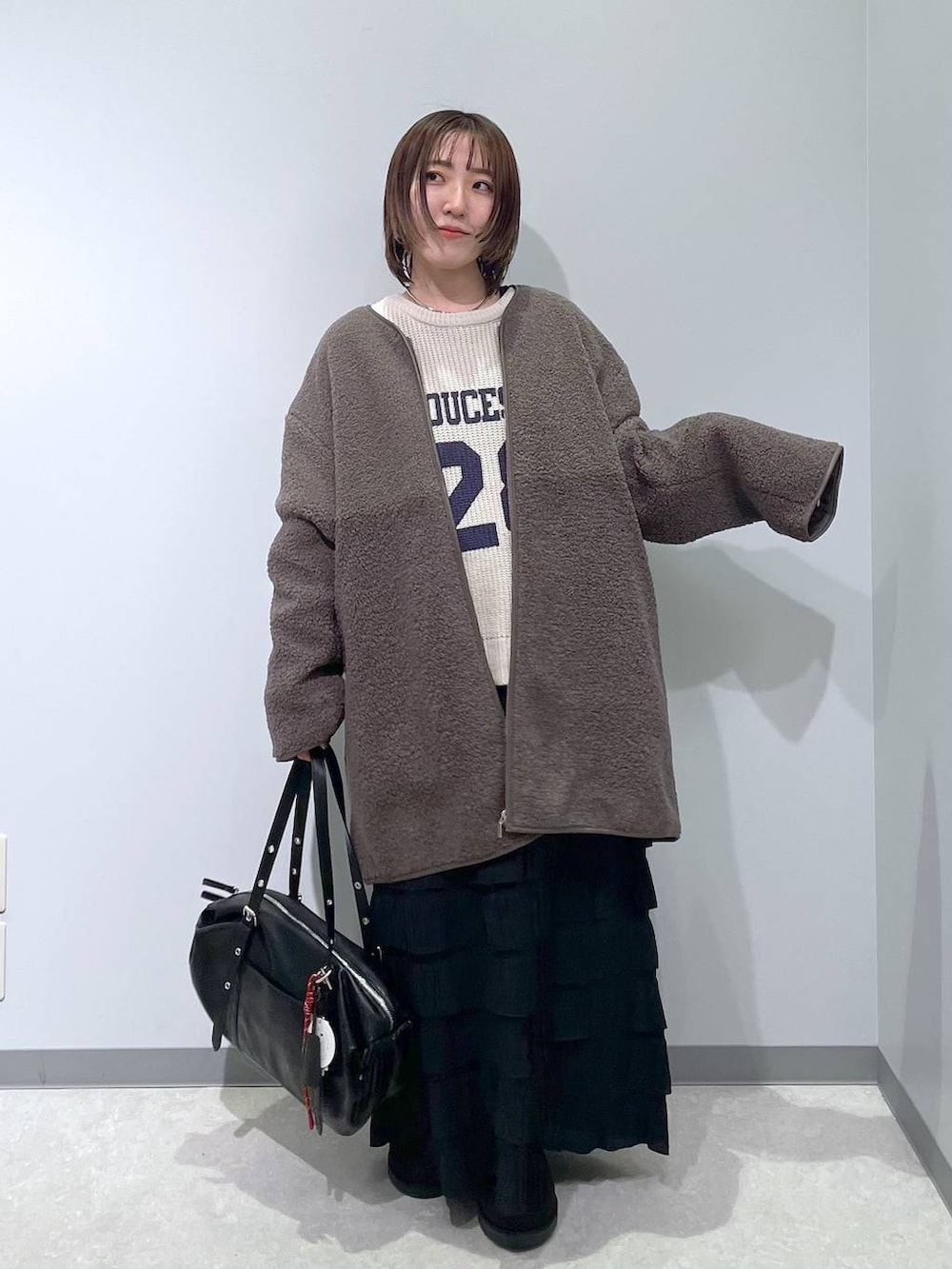 ブラック系のスカート、ブラウン系のその他アウター、ブラック系のブーツを着用したレディースの冬コーディネートの3枚目の写真