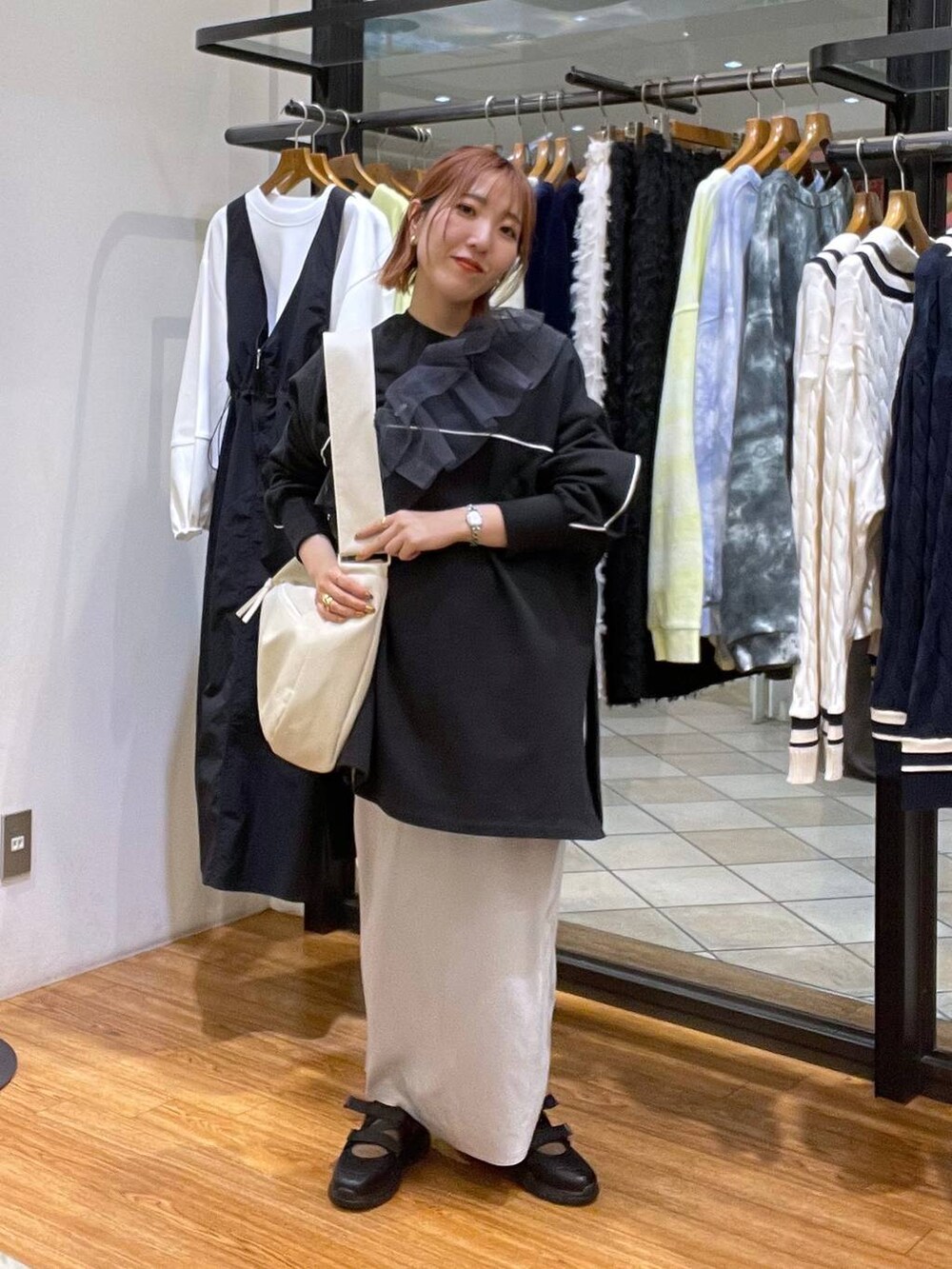 ホワイト系のショルダーバッグ、グレー系のスカート、ブラック系のスニーカーを着用したレディースの春コーディネートの3枚目の写真