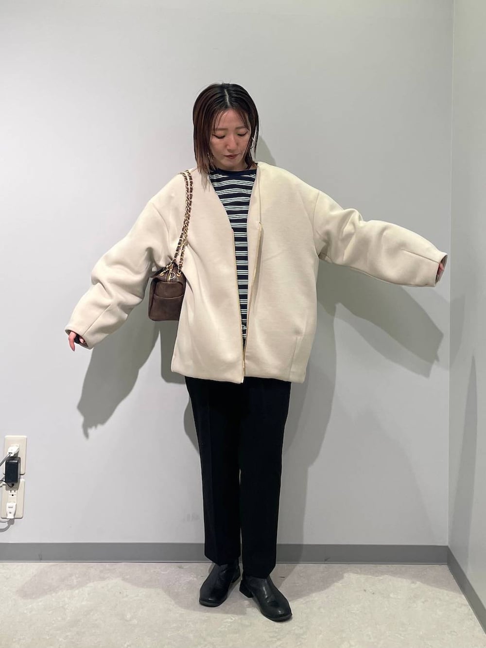 ホワイト系のブルゾン、ブラウン系のショルダーバッグ、ブラック系のスラックスを着用したレディースの春コーディネートの4枚目の写真