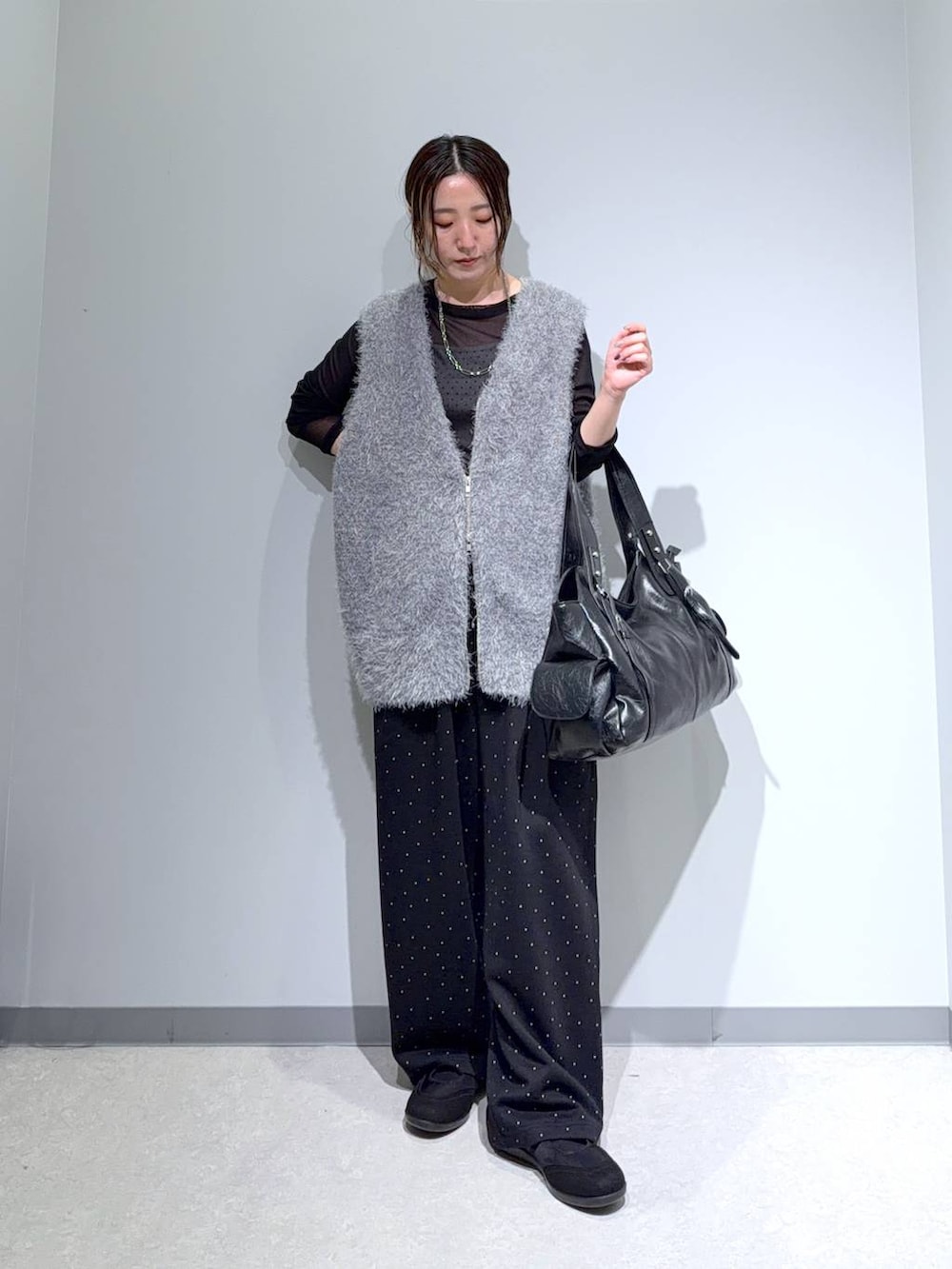ブラック系のパンプス、ブラック系のトートバッグ、グレー系のベストを着用したレディースの秋コーディネートの4枚目の写真