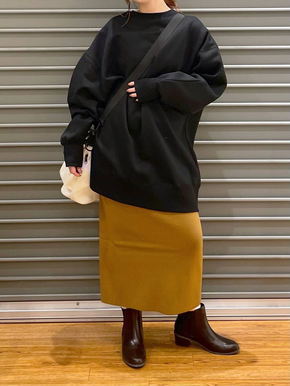 ブラウン系のブーツ、ブラウン系のスカート、ホワイト系のショルダーバッグを着用したレディースの冬コーディネートの2枚目の写真