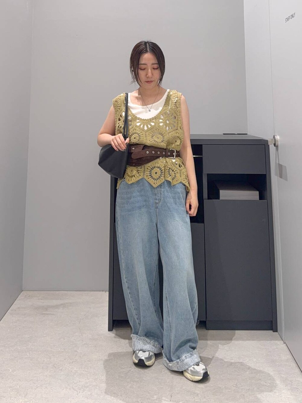 ブルー系のデニムパンツ、ブラック系のショルダーバッグ、ホワイト系のタンクトップを着用したレディースの夏コーディネートの2枚目の写真